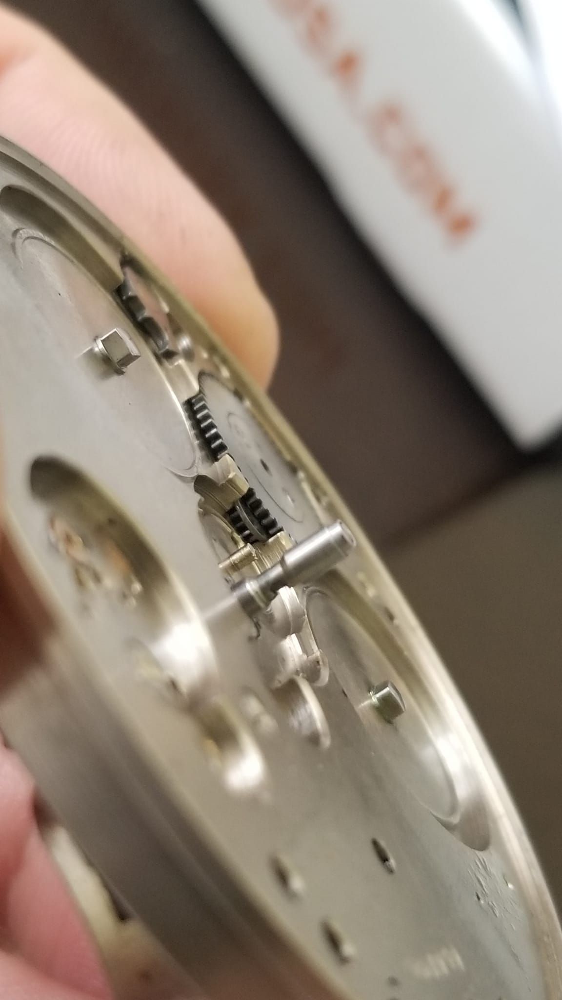 A person is holding a silver watch in their hand.