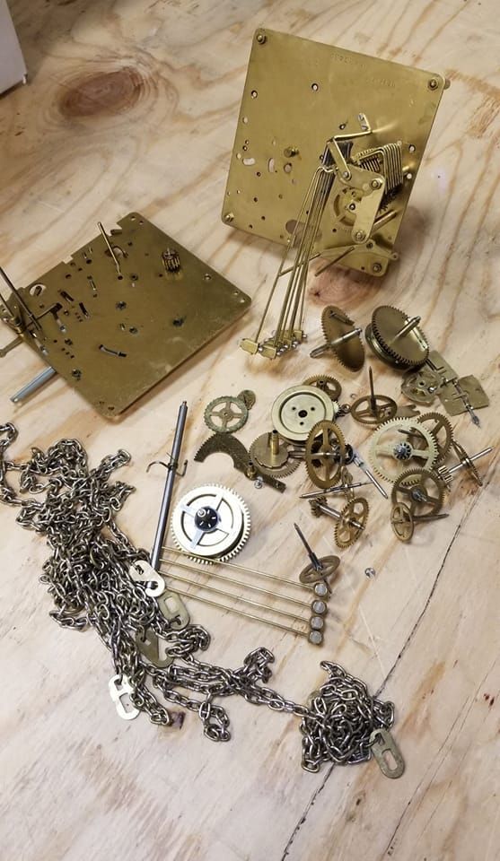 A bunch of clock parts are laying on a wooden table.
