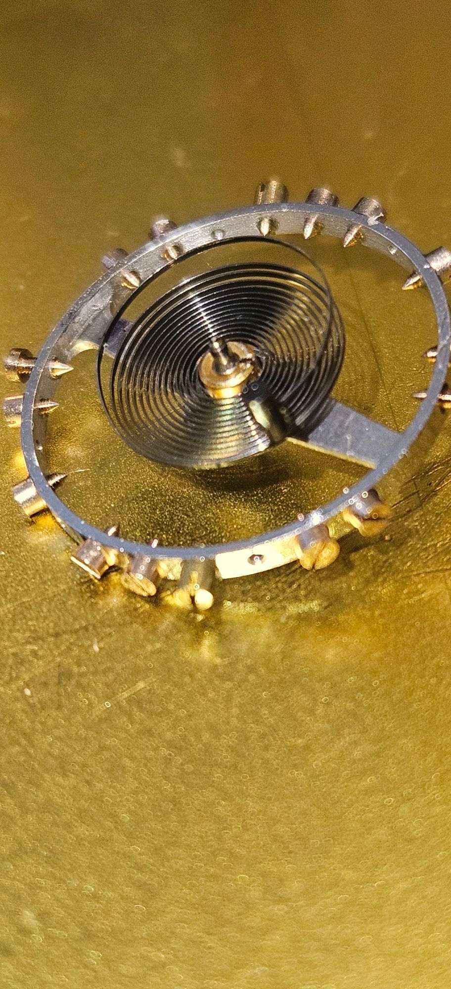 A close up of a metal object on a gold surface.