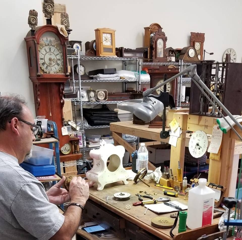 A man is working on a clock in a room full of clocks