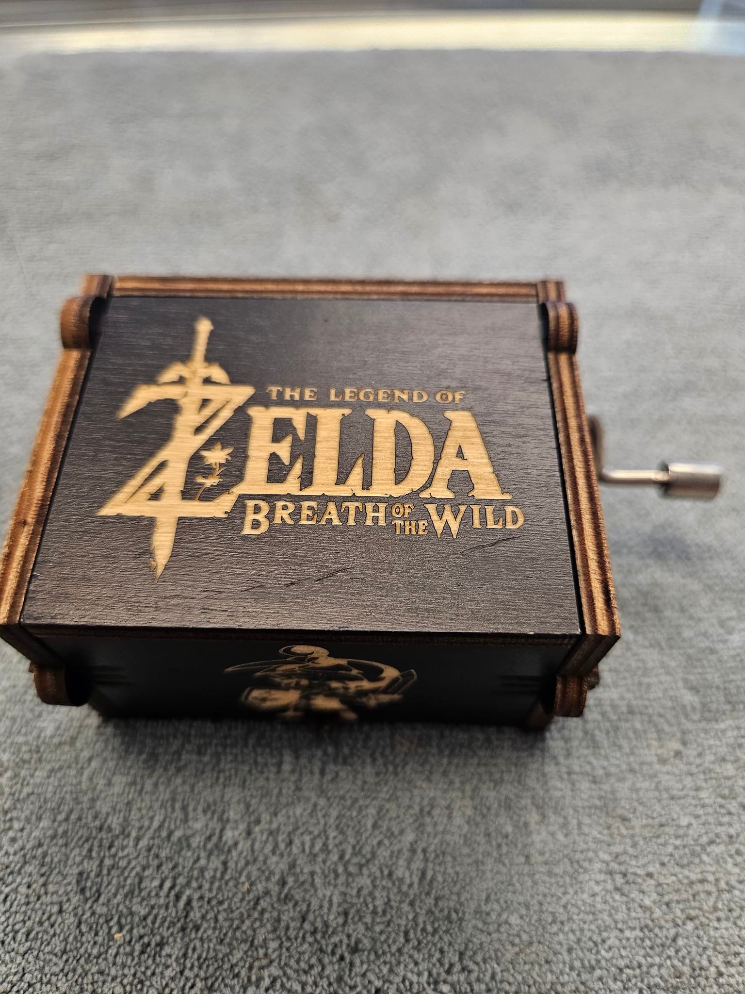 A zelda music box is sitting on a carpet.