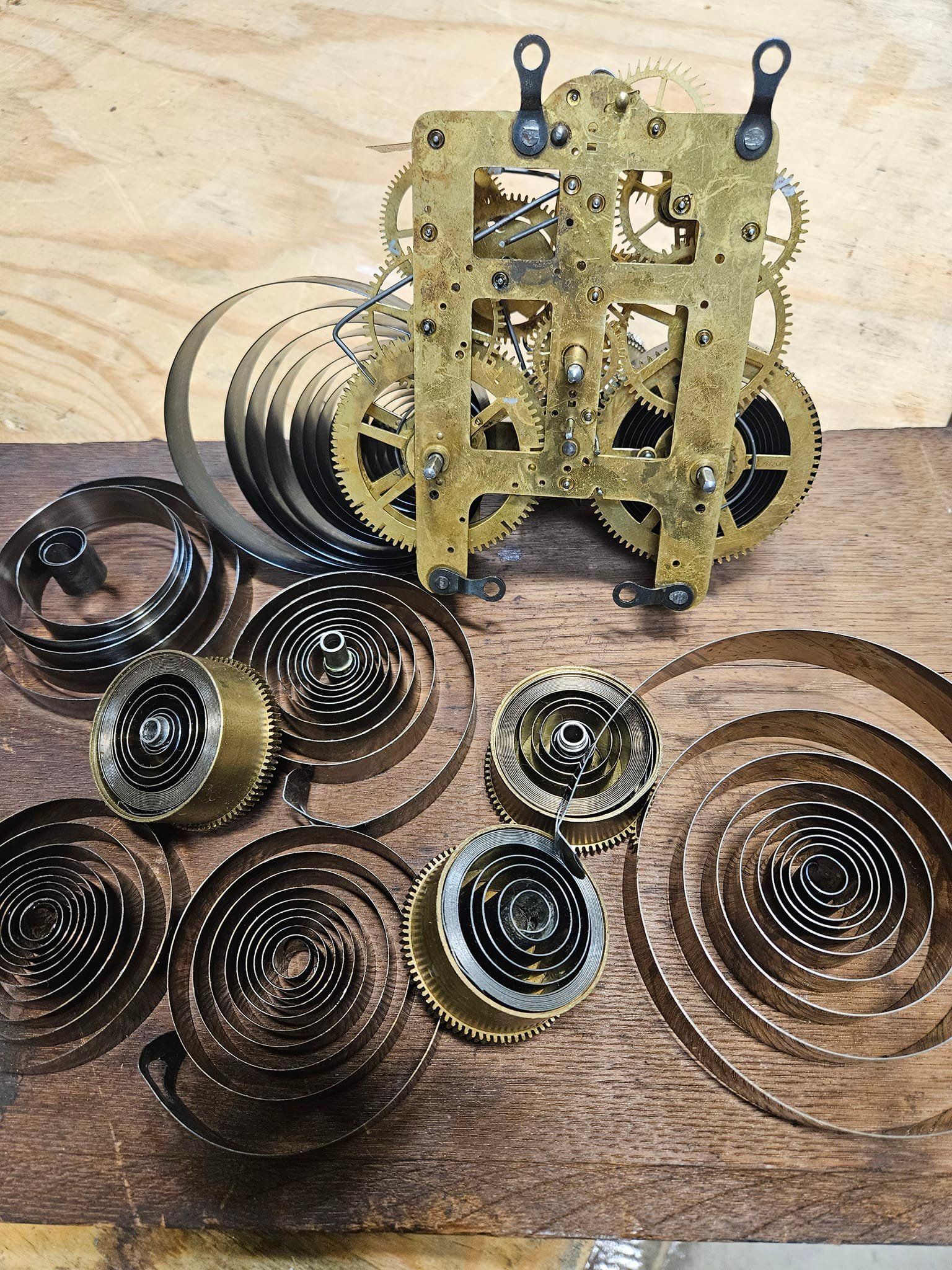 A clock mechanism is sitting on top of a wooden table.