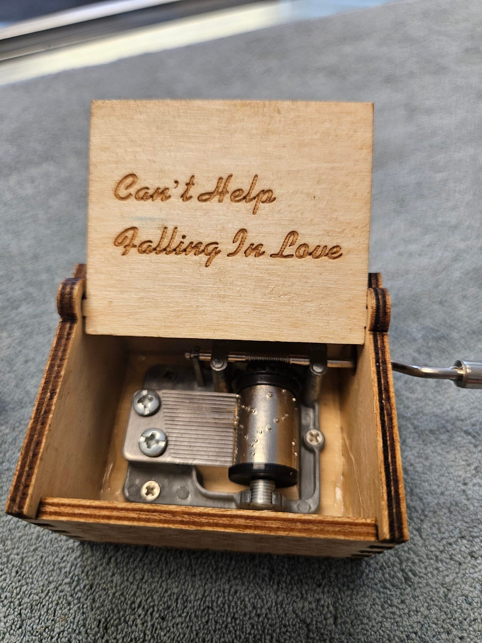 A wooden music box that says can 't help falling in love
