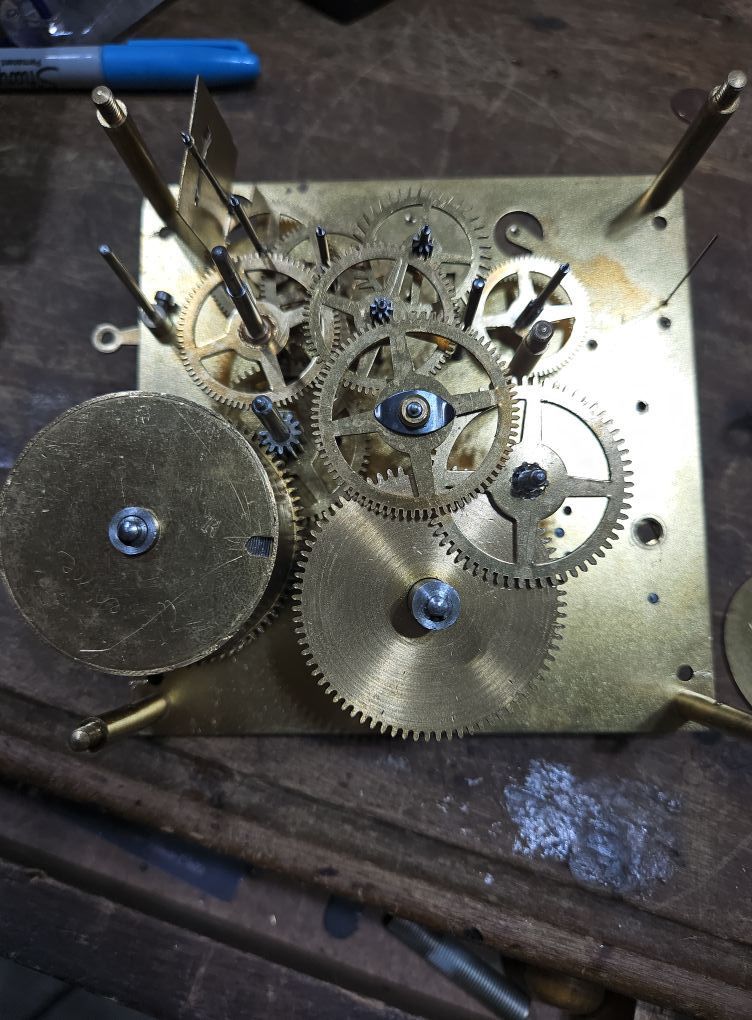 A close up of a clock mechanism with gears on a table.
