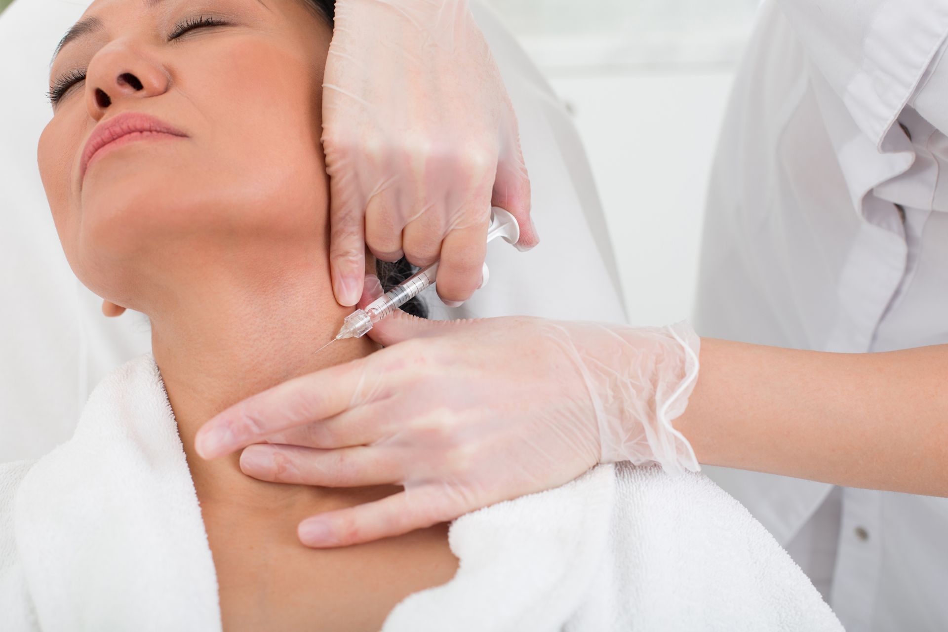 Eine Frau bekommt eine Botox-Injektion in den Nacken.