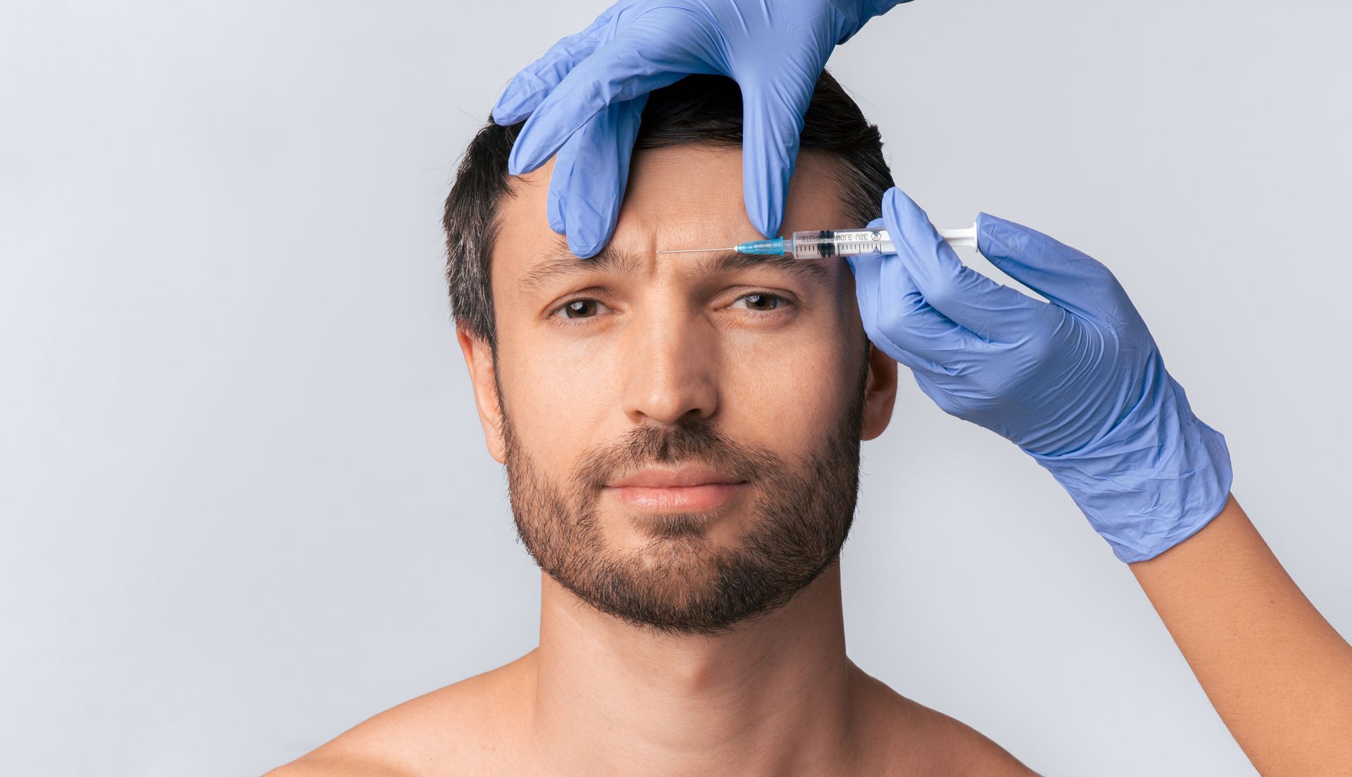 Ein Mann bekommt eine Botox-Injektion in die Stirn.