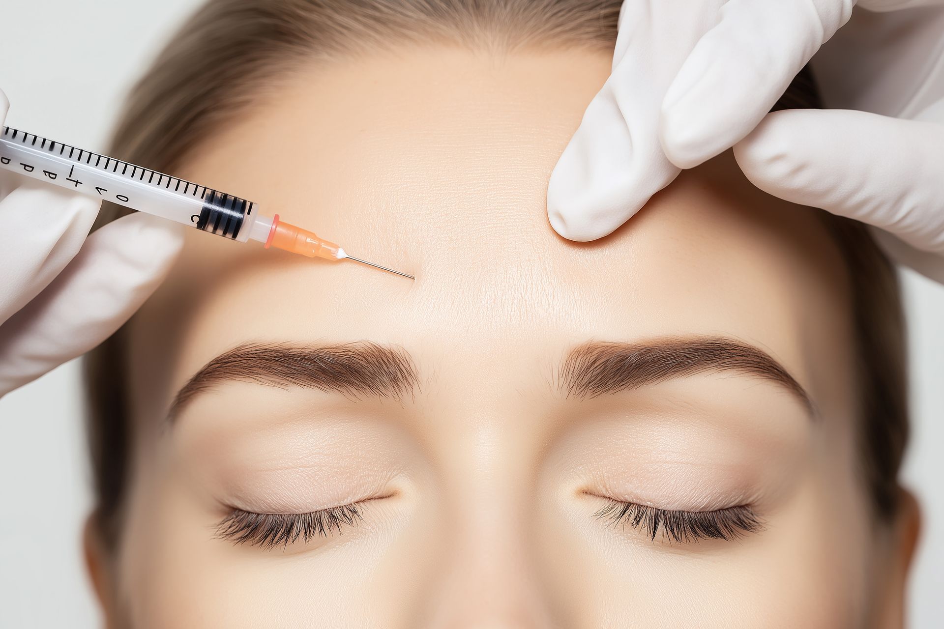 Eine Frau bekommt eine Botox-Injektion in die Stirn.