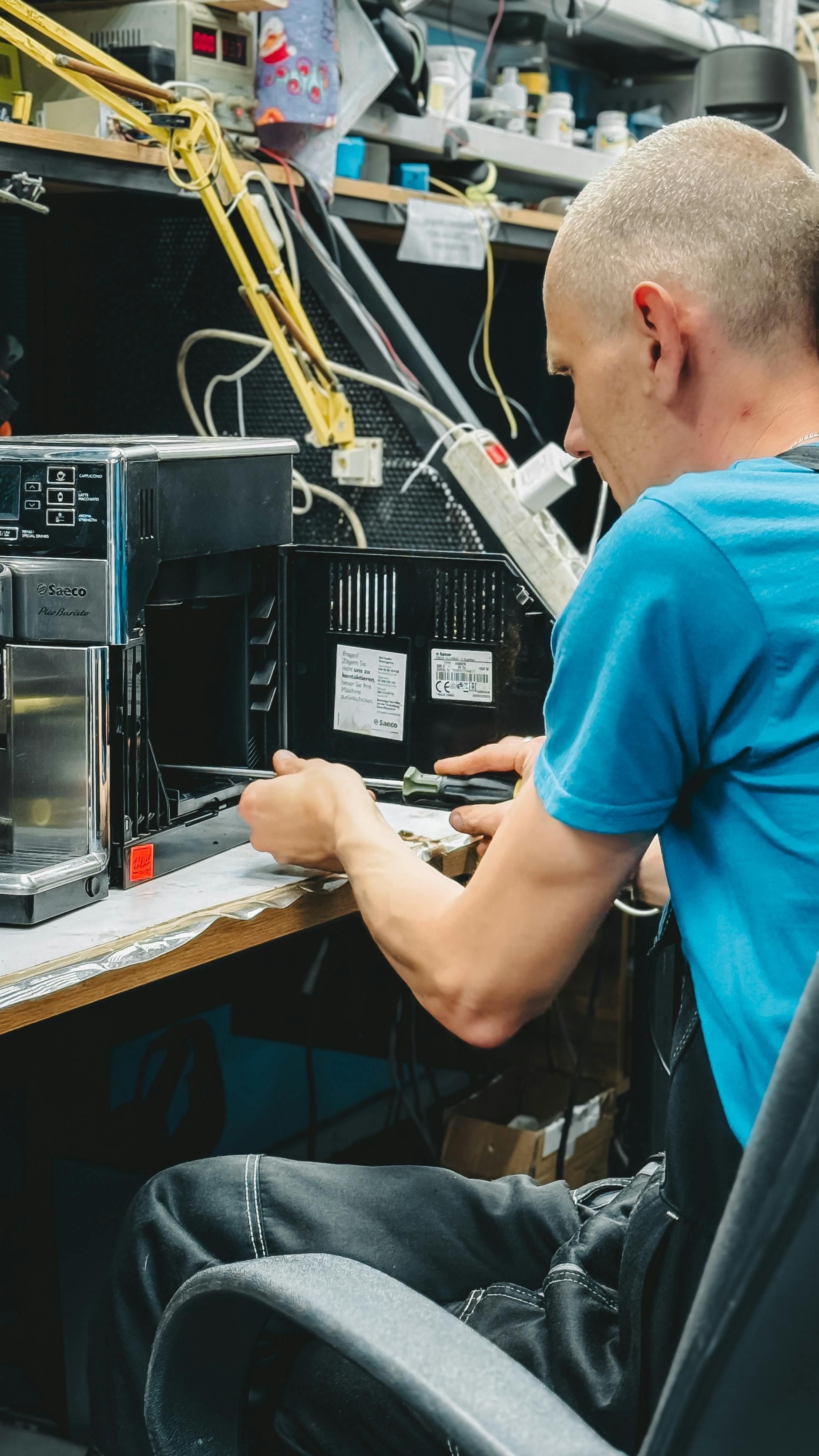 A man is sitting in a chair working on a coffee machine.