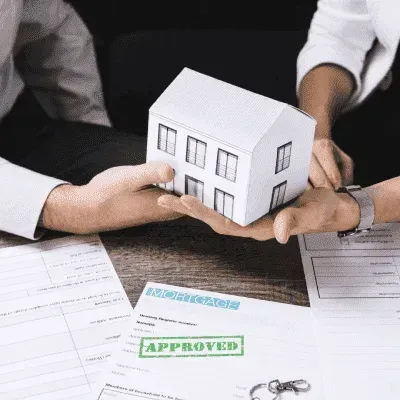 A person is holding a model house in their hands.