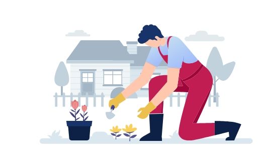 A man is kneeling down in front of a house while planting flowers in pots.