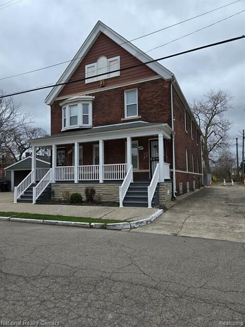 A large brick house with a white porch and stairs