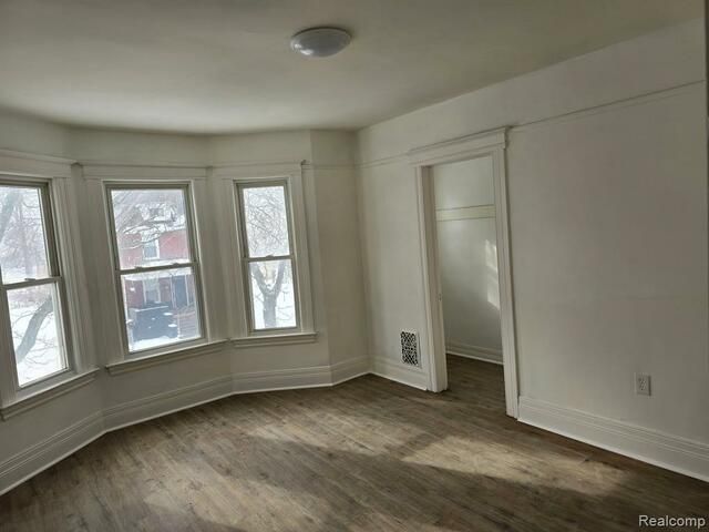 An empty room with a lot of windows and hardwood floors.