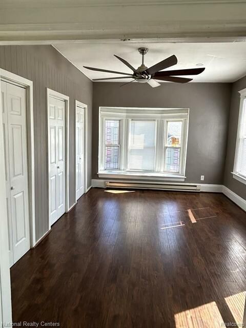 An empty living room with hardwood floors and a ceiling fan.