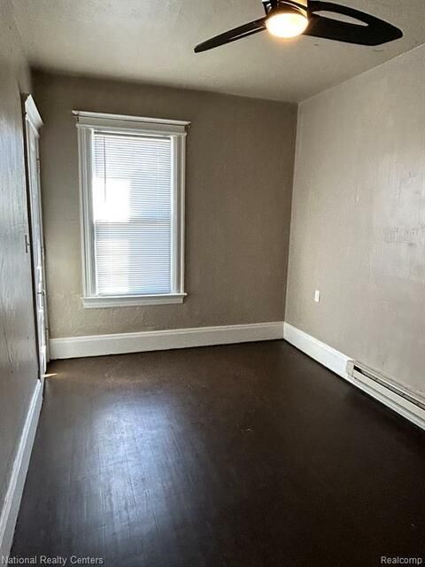 An empty room with a ceiling fan and a window.