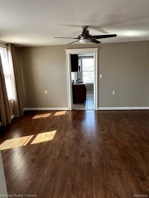 An empty living room with hardwood floors and a ceiling fan.