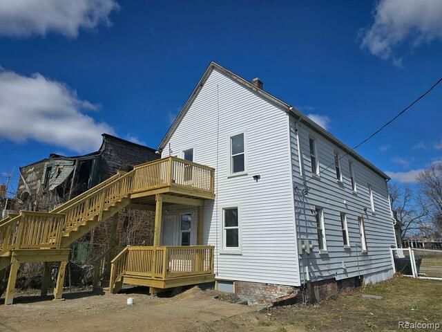 A white house with a wooden deck and stairs.