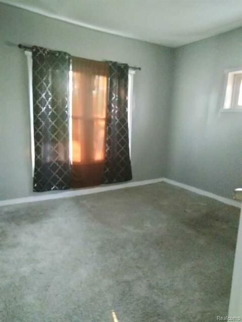 An empty room with a window and curtains.