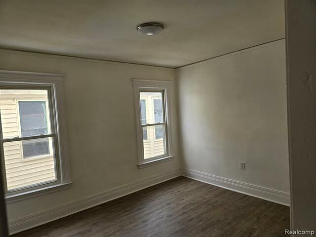 An empty room with two windows and a ceiling light.