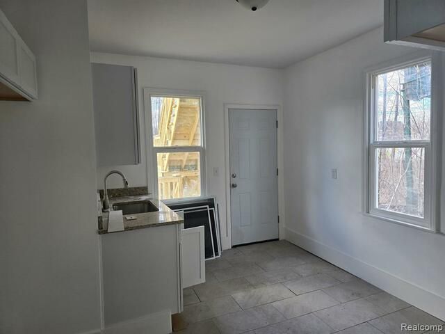 An empty kitchen with a sink and a window.