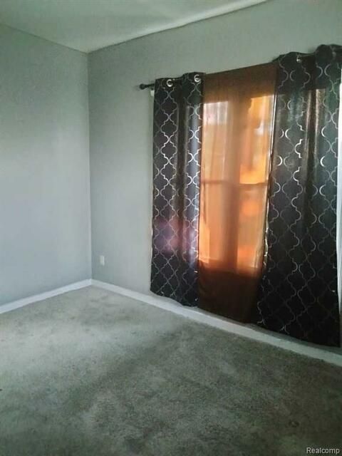An empty room with a window and curtains.