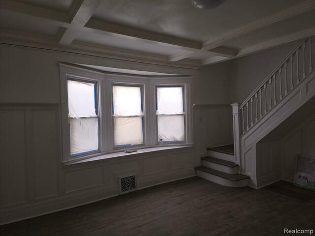 An empty room with stairs and a bay window