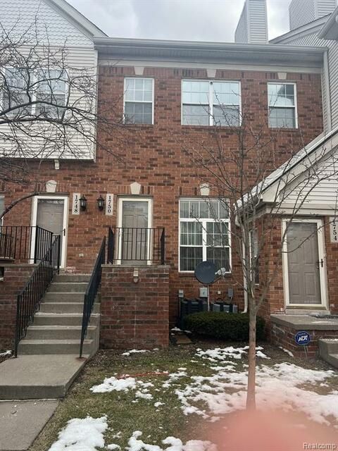 A brick apartment building with stairs leading up to the front door.