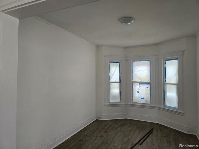An empty room with a bay window and white walls