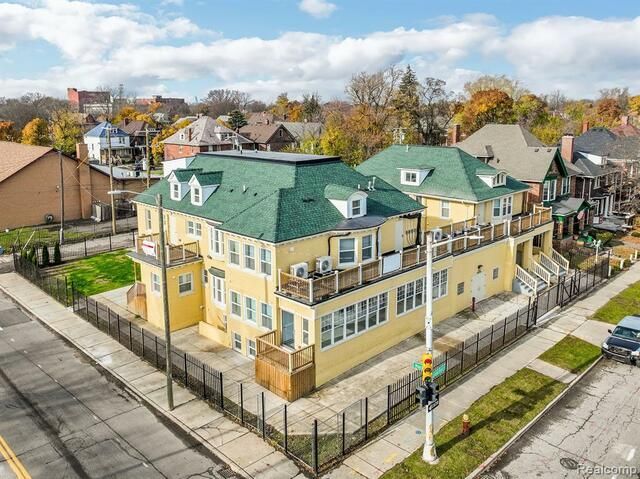 An aerial view of a large yellow building with a green roof surrounded by a fence.