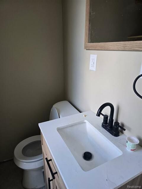 A bathroom with a toilet , sink and mirror.