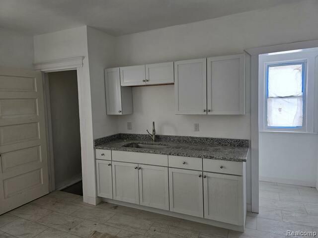 An empty kitchen with white cabinets and granite counter tops