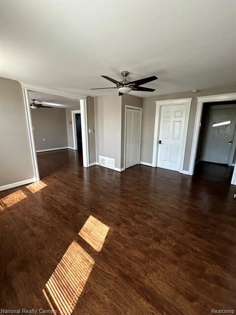A living room with hardwood floors and a ceiling fan.
