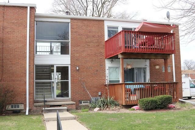 A brick apartment building with a red deck and stairs.