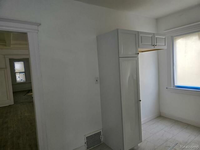 An empty room with a white cabinet and a window.
