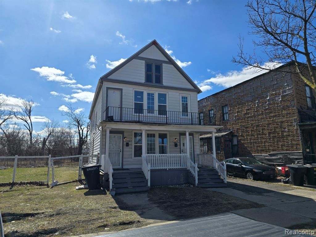 A large white house with a porch and stairs is for sale.