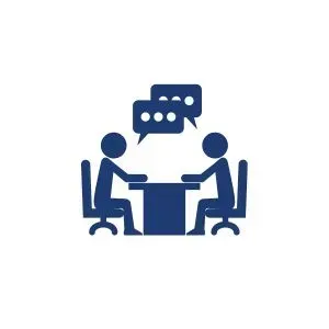 Two people are sitting at a table talking to each other.