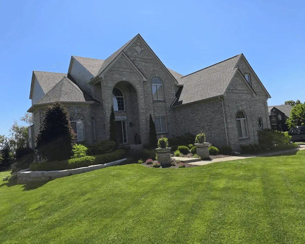 A large brick house with a lush green lawn in front of it.