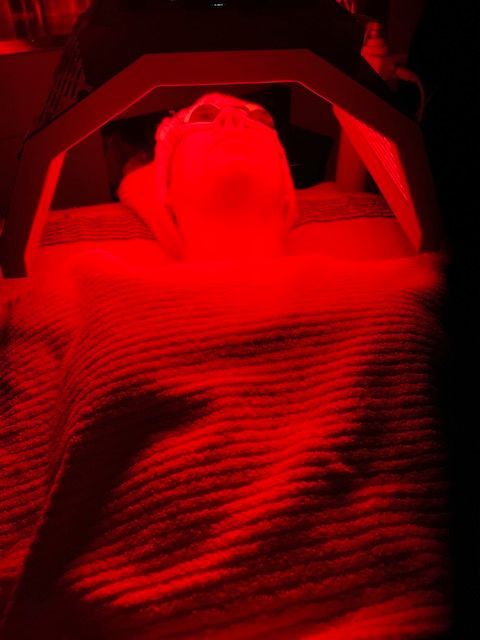 A person is laying on a bed under a red light.
