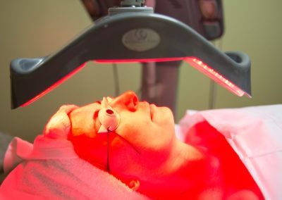 A woman is getting a red light treatment on her face