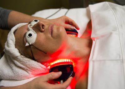 A woman is getting a red light treatment on her face.