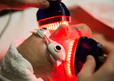 A person is getting a red light treatment on their face.