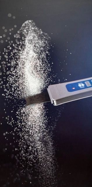 A thermometer is being used to measure salt on a black surface.