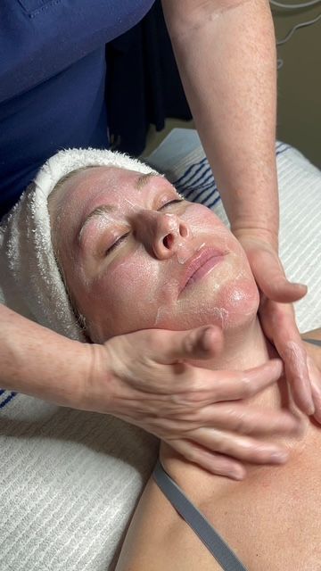 A woman with a towel on her head is getting a massage on her face.