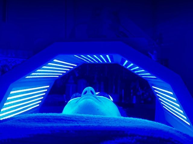 A person is getting a blue light treatment on their face.