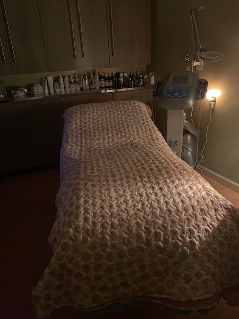 A bed in a dark room with a blanket on it.