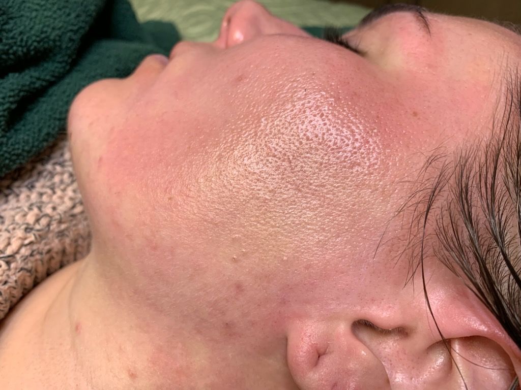 A close up of a woman 's face with a green towel covering her head.