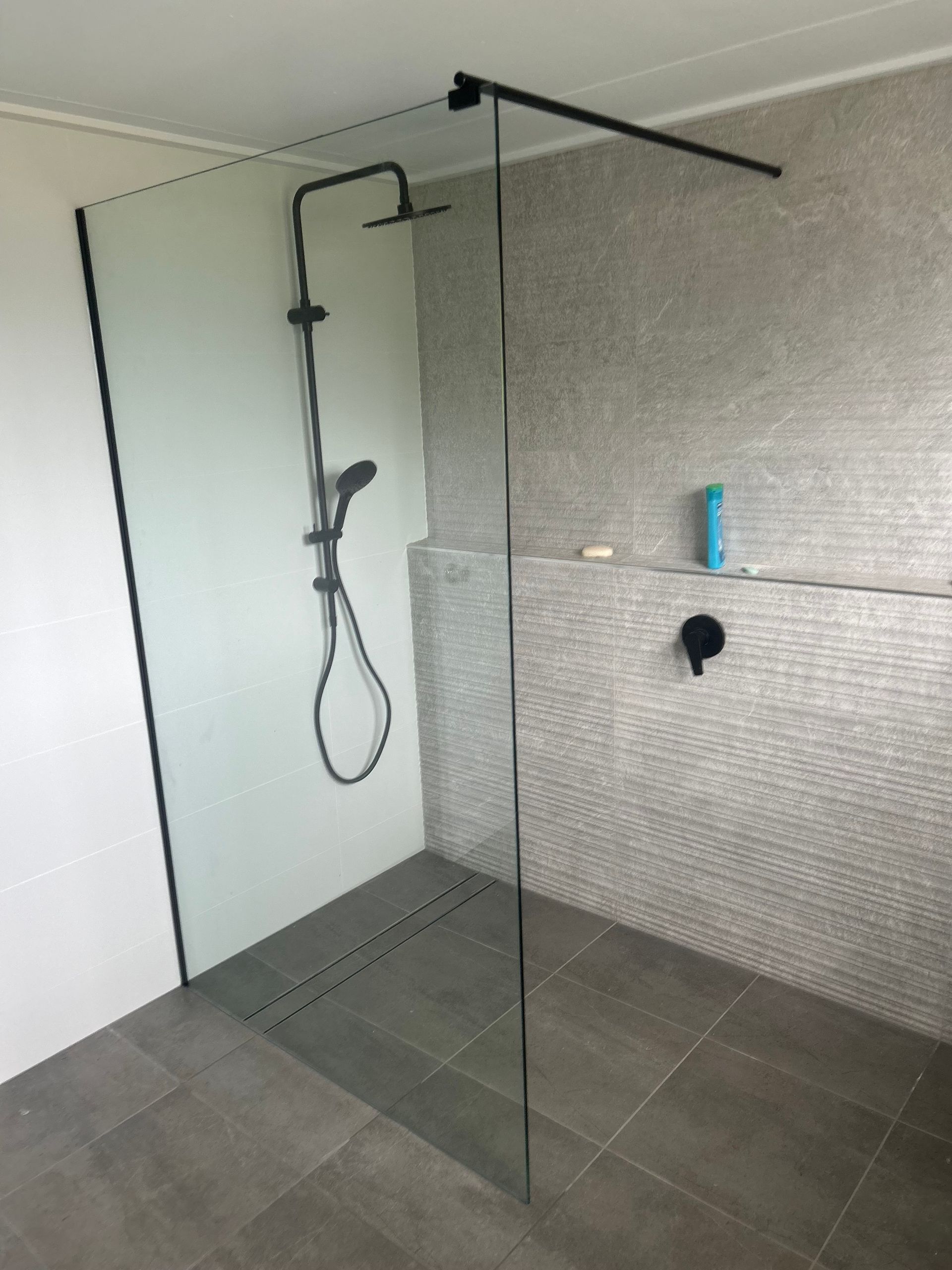 A bathroom with a walk in shower and a black shower head — Innisfail Glass & Aluminium In Innisfail, QLD
