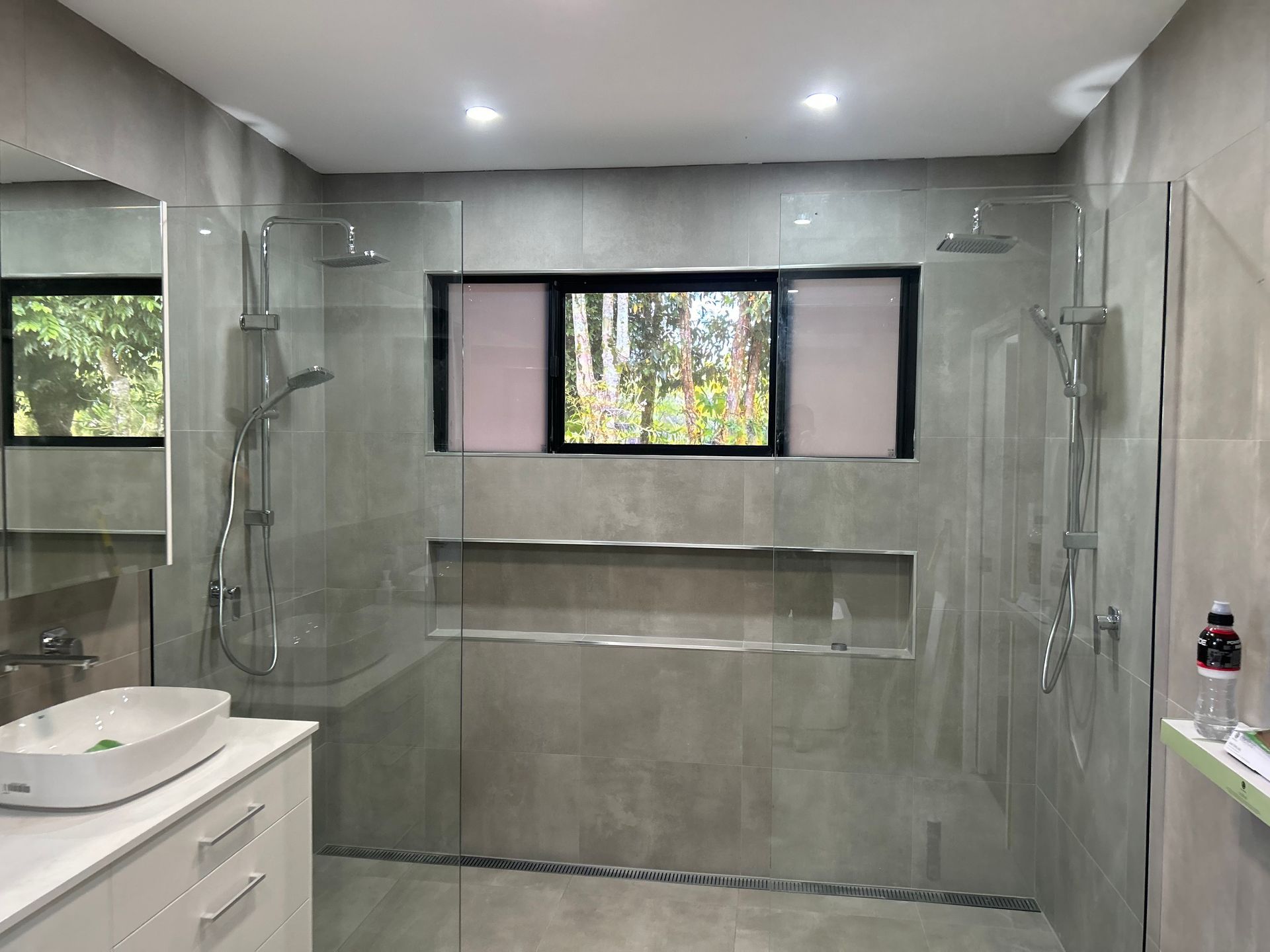 A bathroom with a walk in shower , sink , mirror and window — Innisfail Glass & Aluminium In Innisfail, QLD