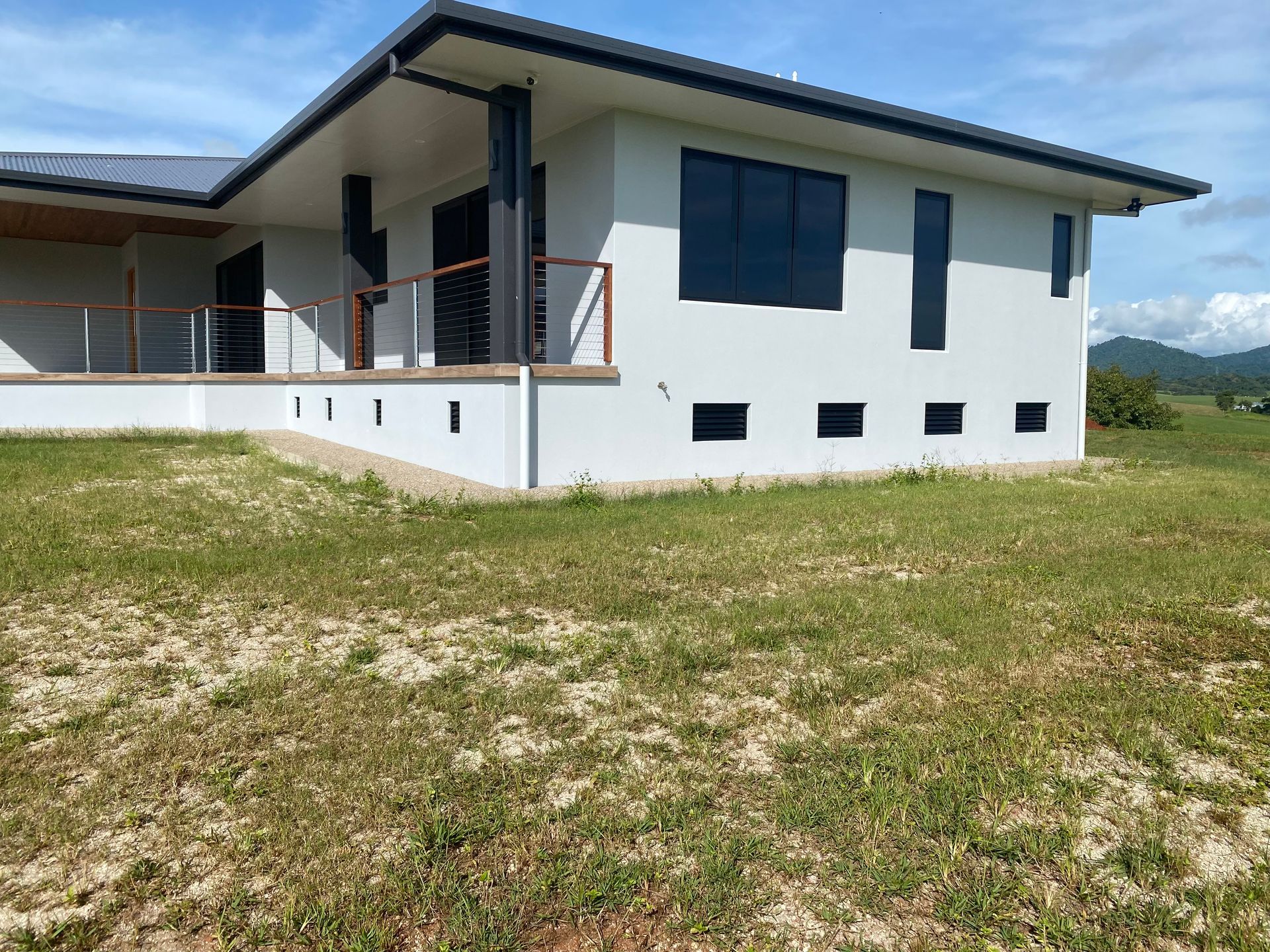 A white house is sitting in the middle of a grassy field — Innisfail Glass & Aluminium In Innisfail, QLD
