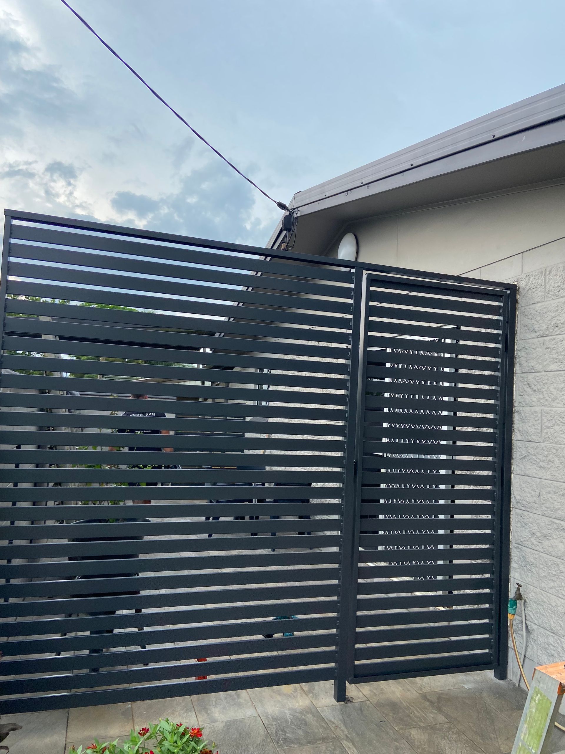 A black fence is sitting in front of a house — Innisfail Glass & Aluminium In Innisfail, QLD