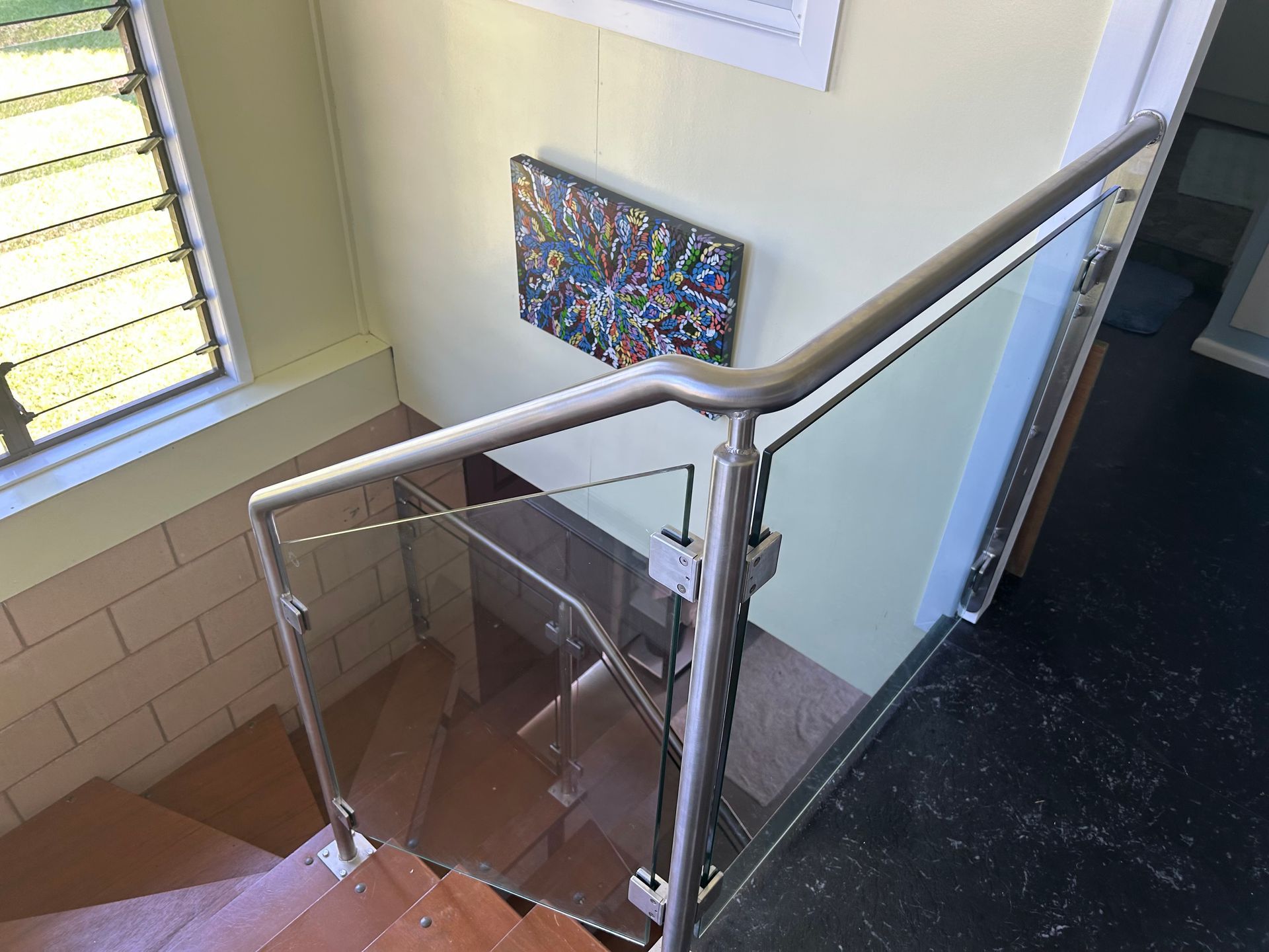 A staircase with a glass railing and a painting on the wall — Innisfail Glass & Aluminium In Innisfail, QLD